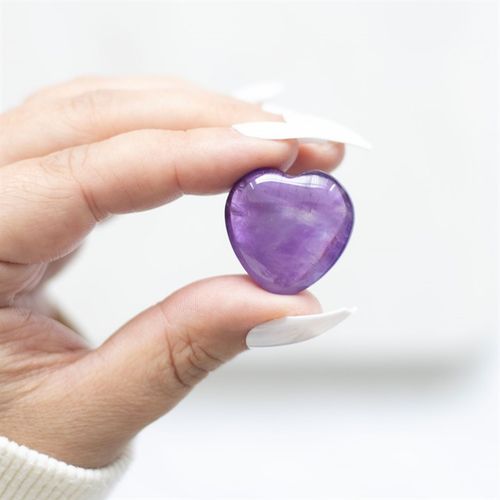 A hand gently holding a polished Amethyst Crystal Heart. This healing stone promotes emotional balance, stress relief, and spiritual clarity, making it a perfect gift for mindfulness, meditation, and energy healing.