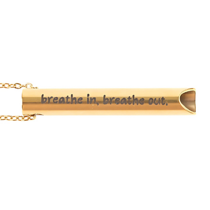  A close-up of the Anti-Anxiety Breathing Necklace, a gold-tone stainless steel pendant engraved with "breathe in, breathe out" for stress relief and mindfulness.