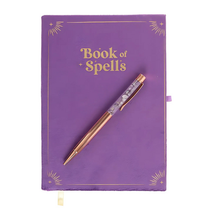 The Book of Spells Journal, a purple velvet hardcover notebook with gold detailing and a matching crystal-infused pen, perfect for journaling and spellcraft.