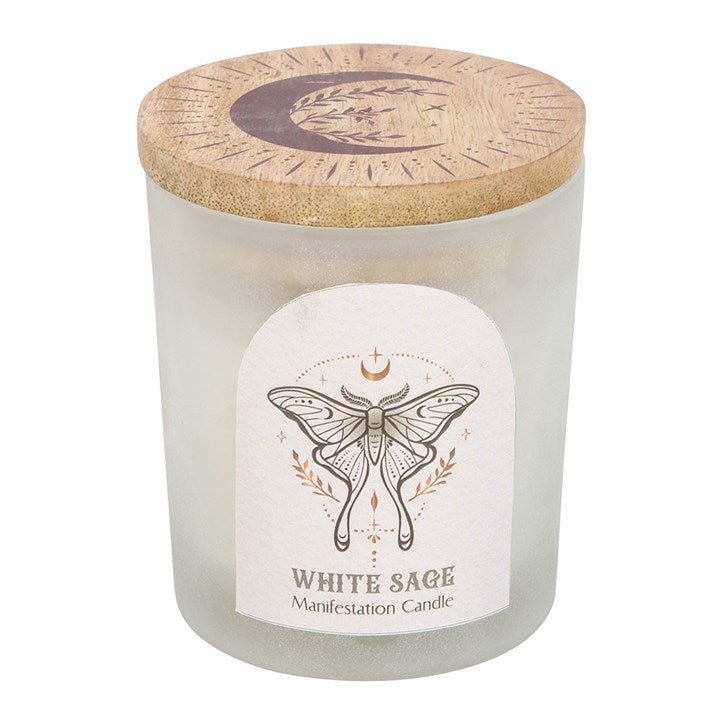 A close up of a white candle with healing crystals in a frosted glass container. The label has a spiritual moth and the lid is wooden with a moon engraving, against a white background.