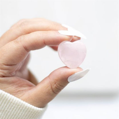 A hand gently holding a polished Rose Quartz Crystal Heart. This healing stone promotes self-love, emotional balance, and heart chakra healing, making it a perfect gift for relationships, mindfulness, and spiritual well-being.